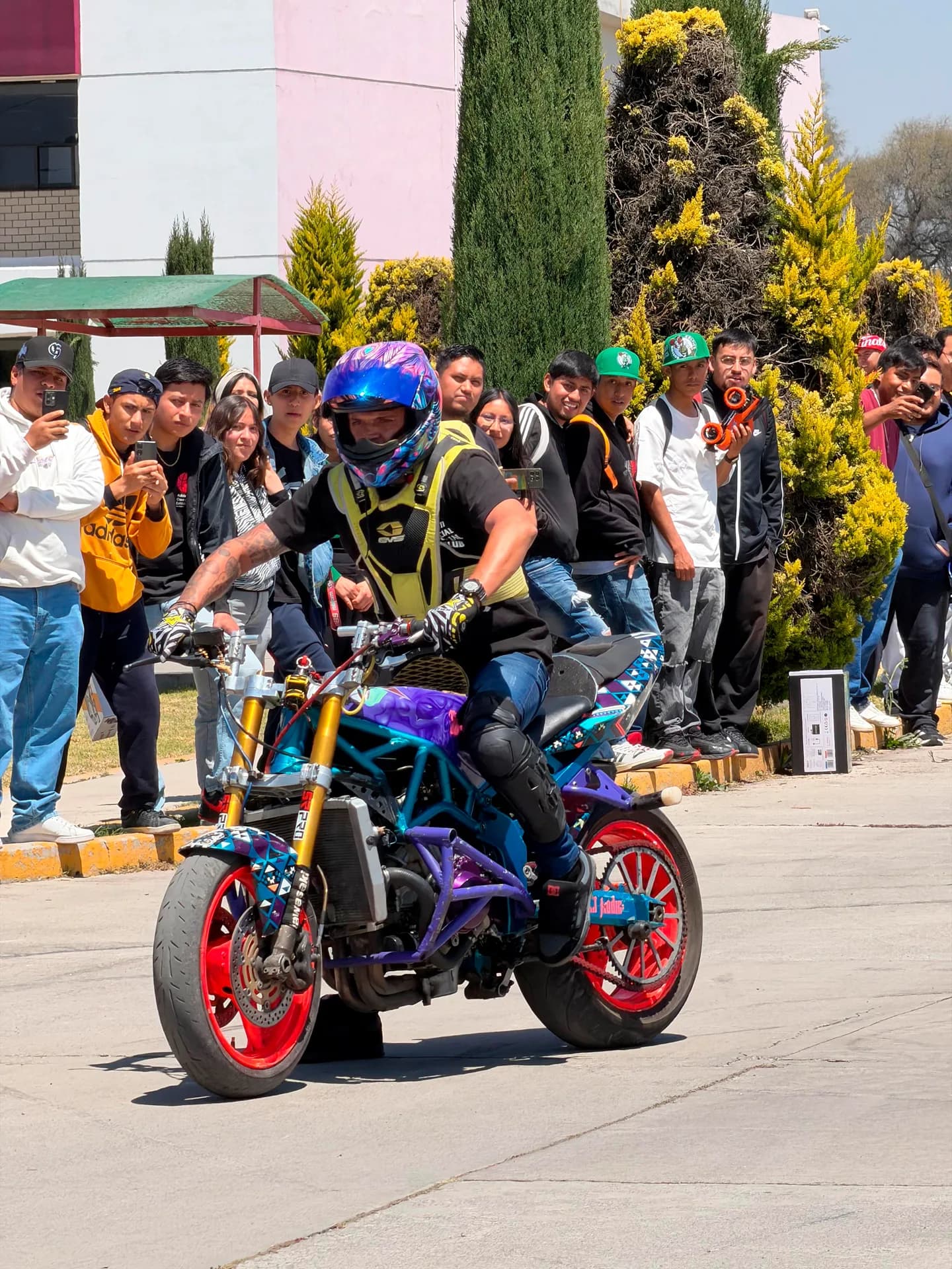 Comunidad universitaria observando una demostración con motocicleta
