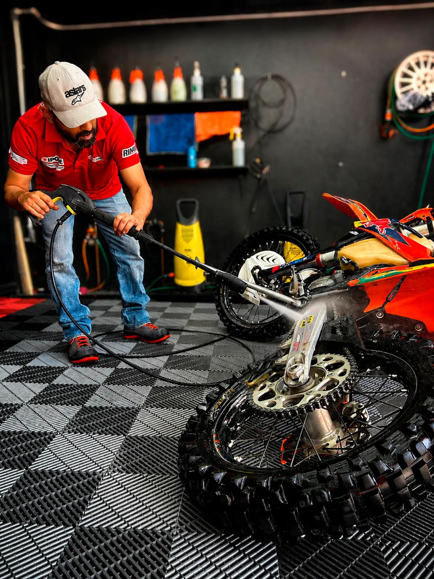Lavado de una motocicleta off-road con una persona y herramienta de agua en el área de trabajo